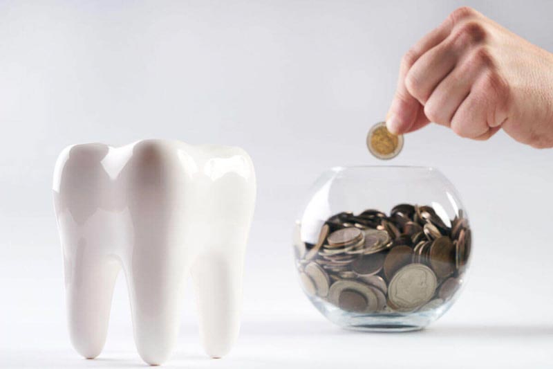 A picture of money going into a jar. A tooth is also in the for-ground.