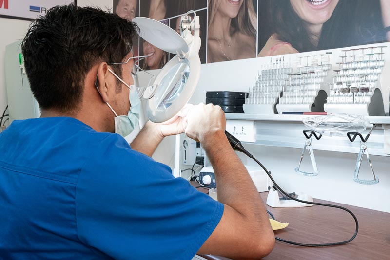 A SOTA Dental lab technician in Cancun works on a dental crown using a magnification tool