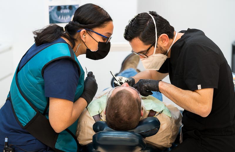 Dr. Diego, dentist in Los Algodones at SOTA Dental, is performing dental work with the help of his female assistant.