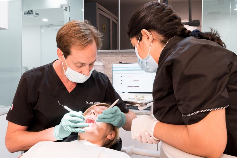 Dr. Sforzina, a dentist at SOTA Dental in Cancun performs dental work on a female patient.