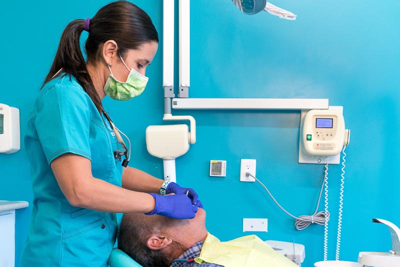 Dr. Alejandra, a prosthodontist as SOTA Dental Playa del Carmen, performs dental work on a male patient.